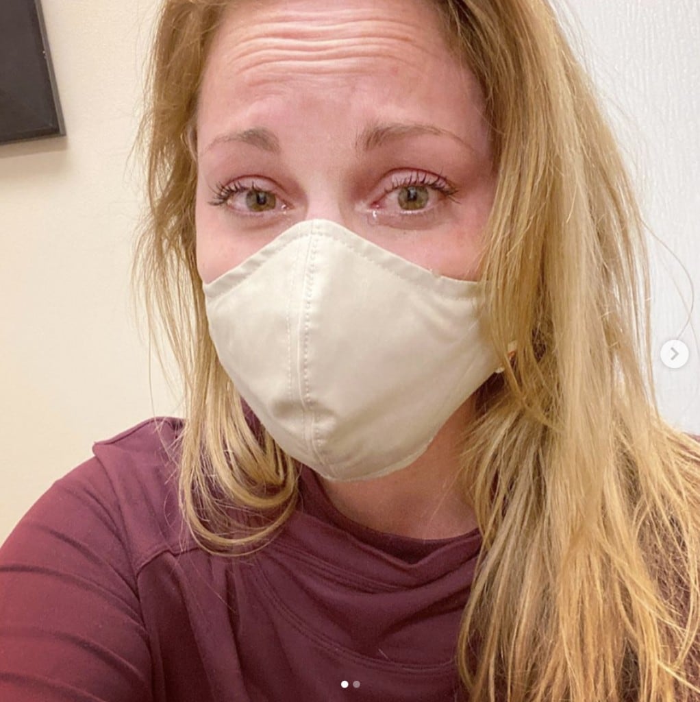 woman wearing protective face mask stares into camera with red teary eyes