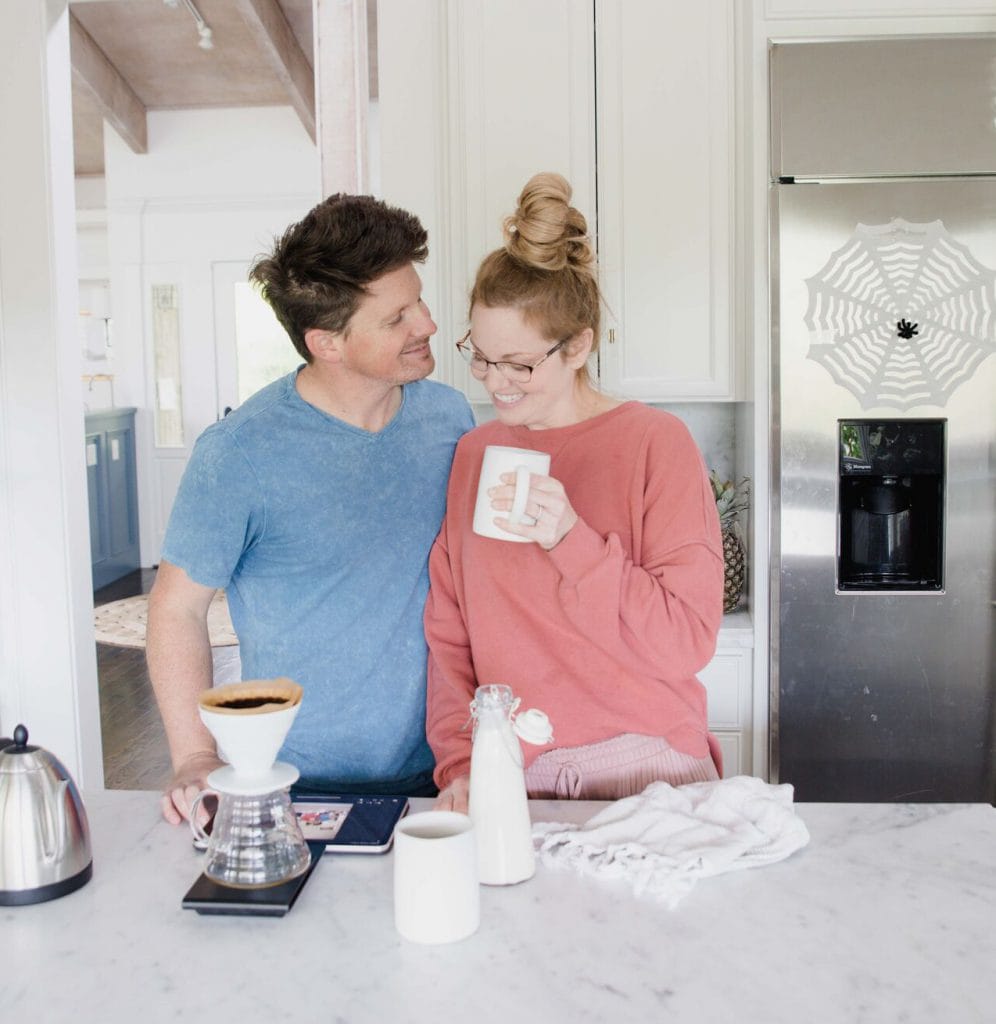 Man and woman stand in kitchen in close proximity enjoying a cup of coffee