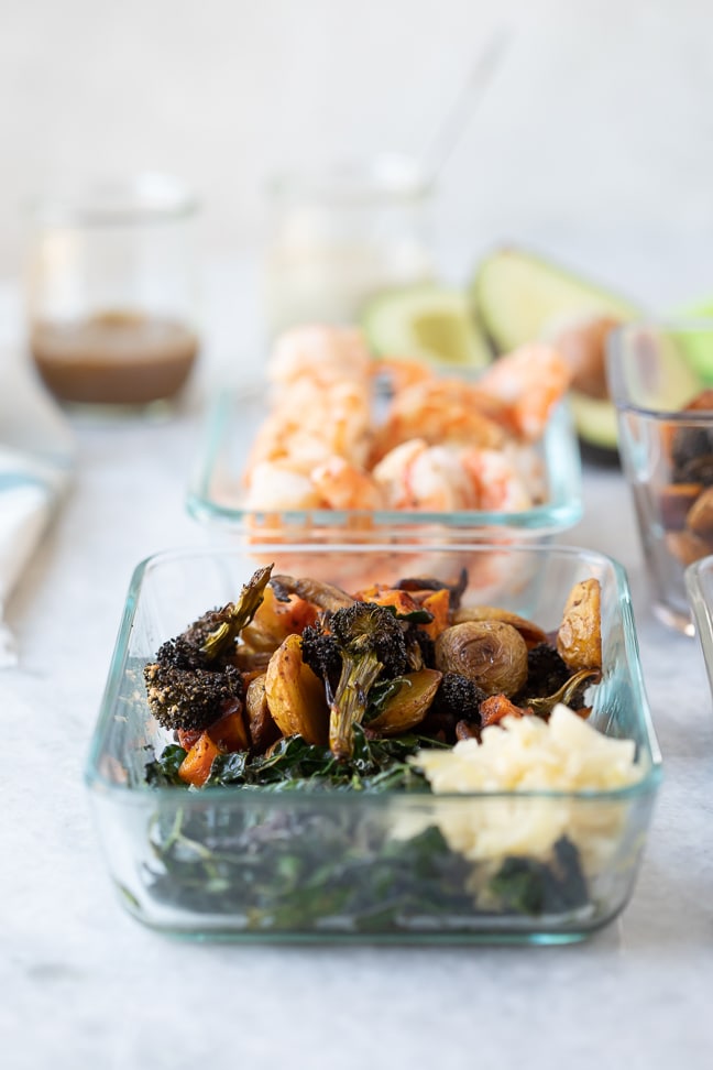 Roasted veggie bowl and a bowl of cooked shrimp displayed on a white marble counter