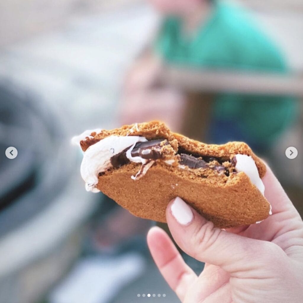 Up close picture of a s'more - melting chocolate and gooey marshmallow squeezed between two crunch graham crackers