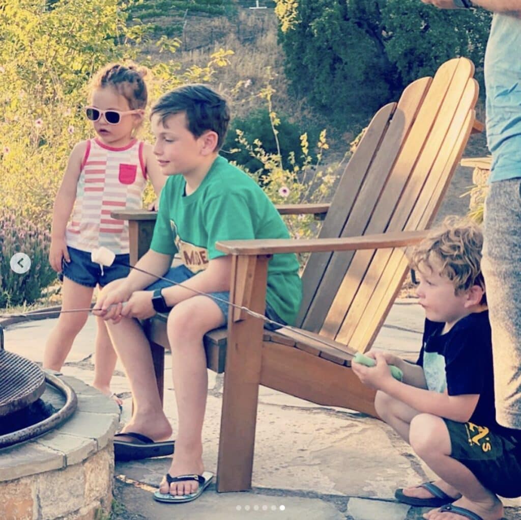 children gather around a stone fire pit to toast marshmallows 