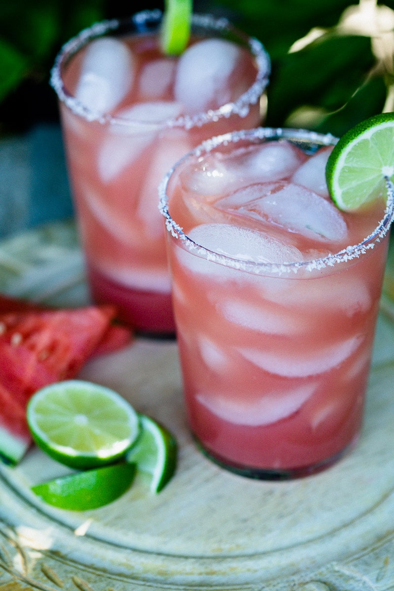 Watermelon Margaritas (Paleo & Refined Sugar-Free) served in glass tumblers full of ice and garnished with a lime next pieces of fresh watermelon and slices of lime