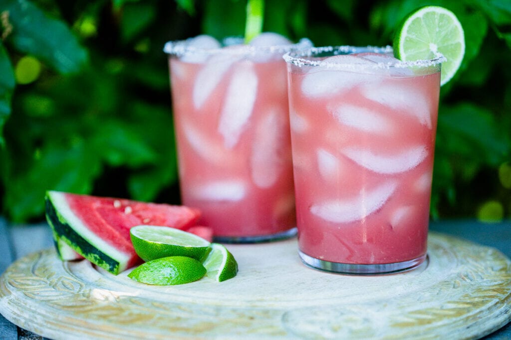 Watermelon Margaritas (Paleo & Refined Sugar-Free) served in glass tumblers full of ice and garnished with a lime next pieces of fresh watermelon