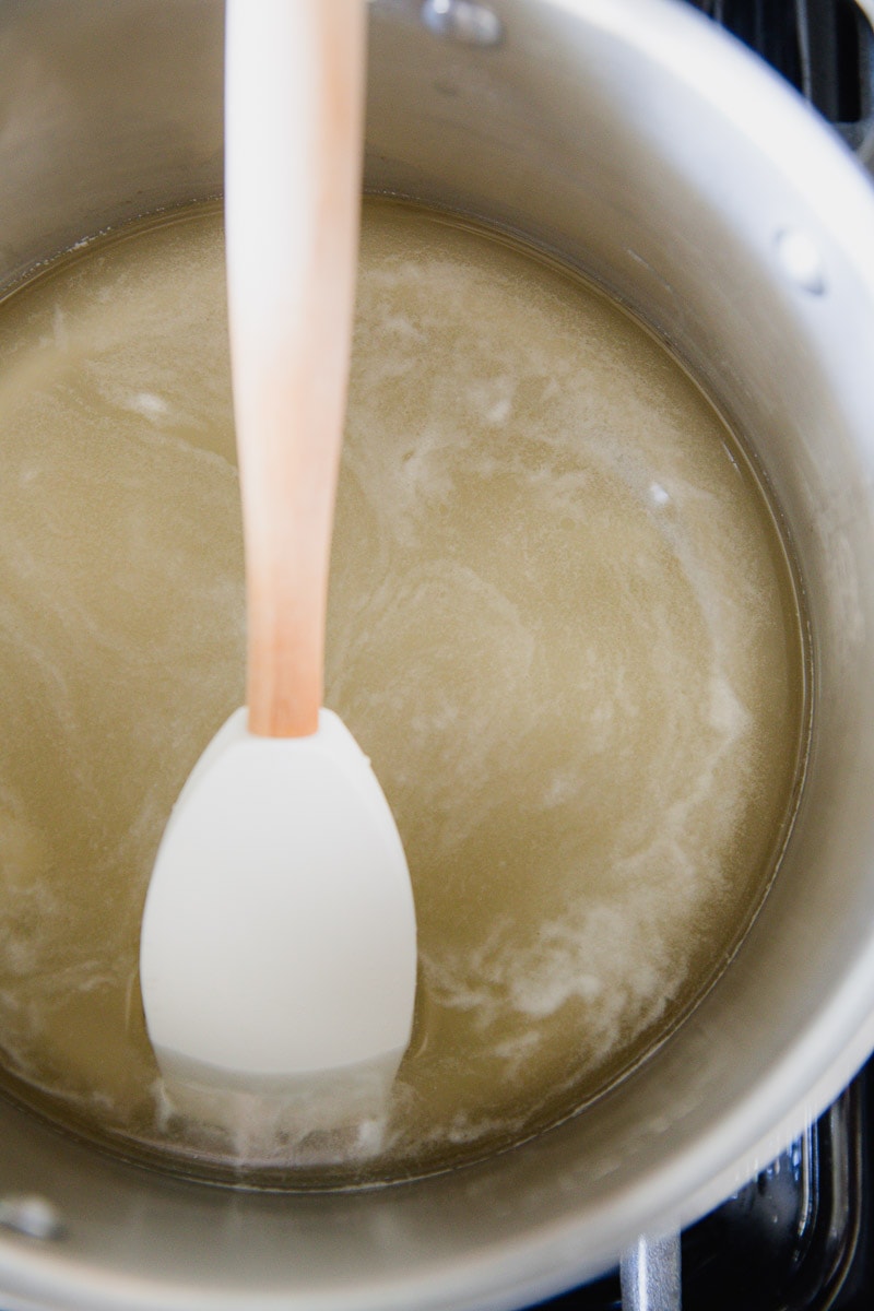 raw honey and water being stirred together in a pot over the stove