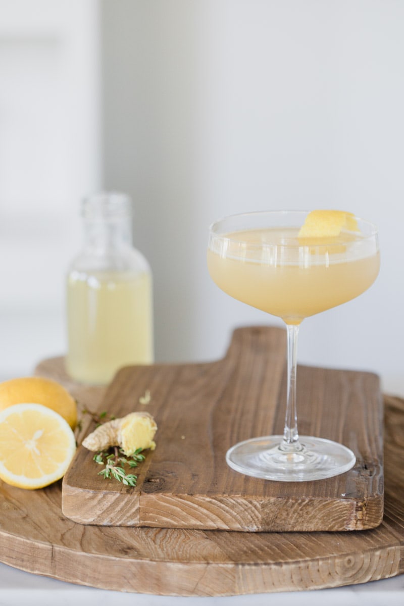 Ginger Thyme Tequila Sour cocktail garnished with lemon placed on wooden cutting boards