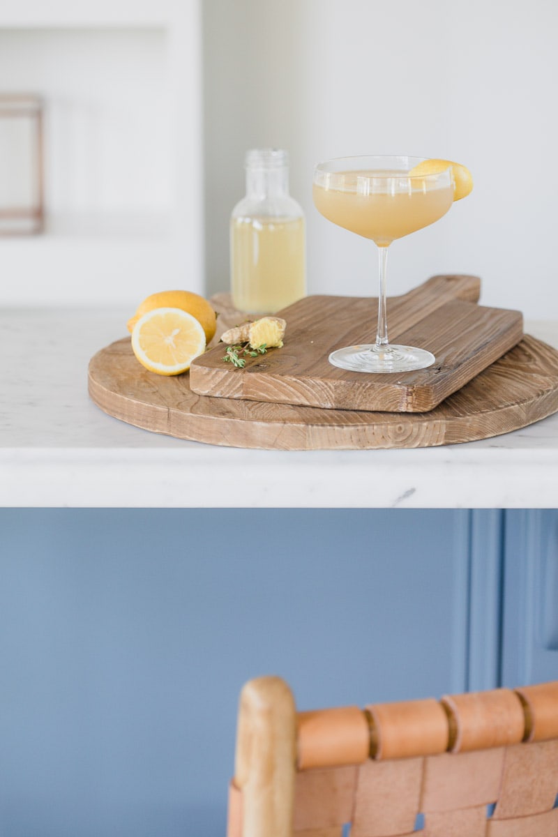 Ginger Thyme Tequila Sour cocktail garnished with lemon placed on wooden cutting boards