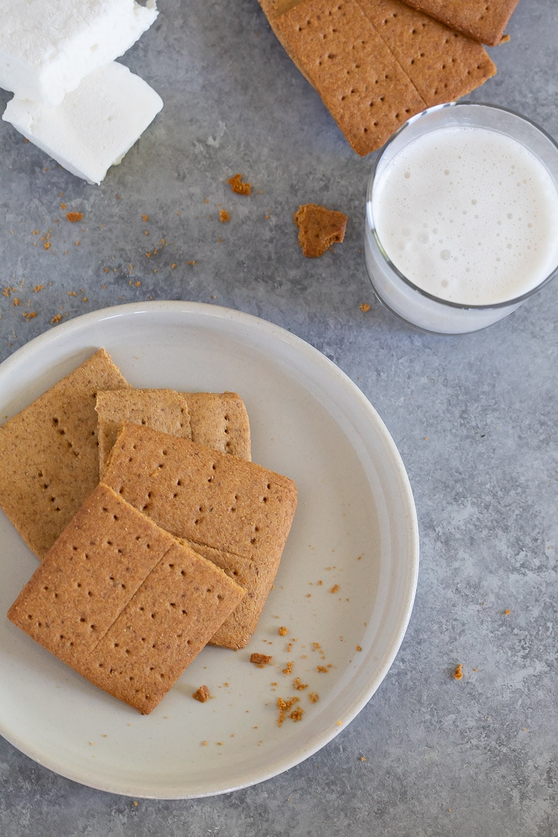 Gluten-Free Graham Crackers on a white plate on gray marble counter next to a glass of milk