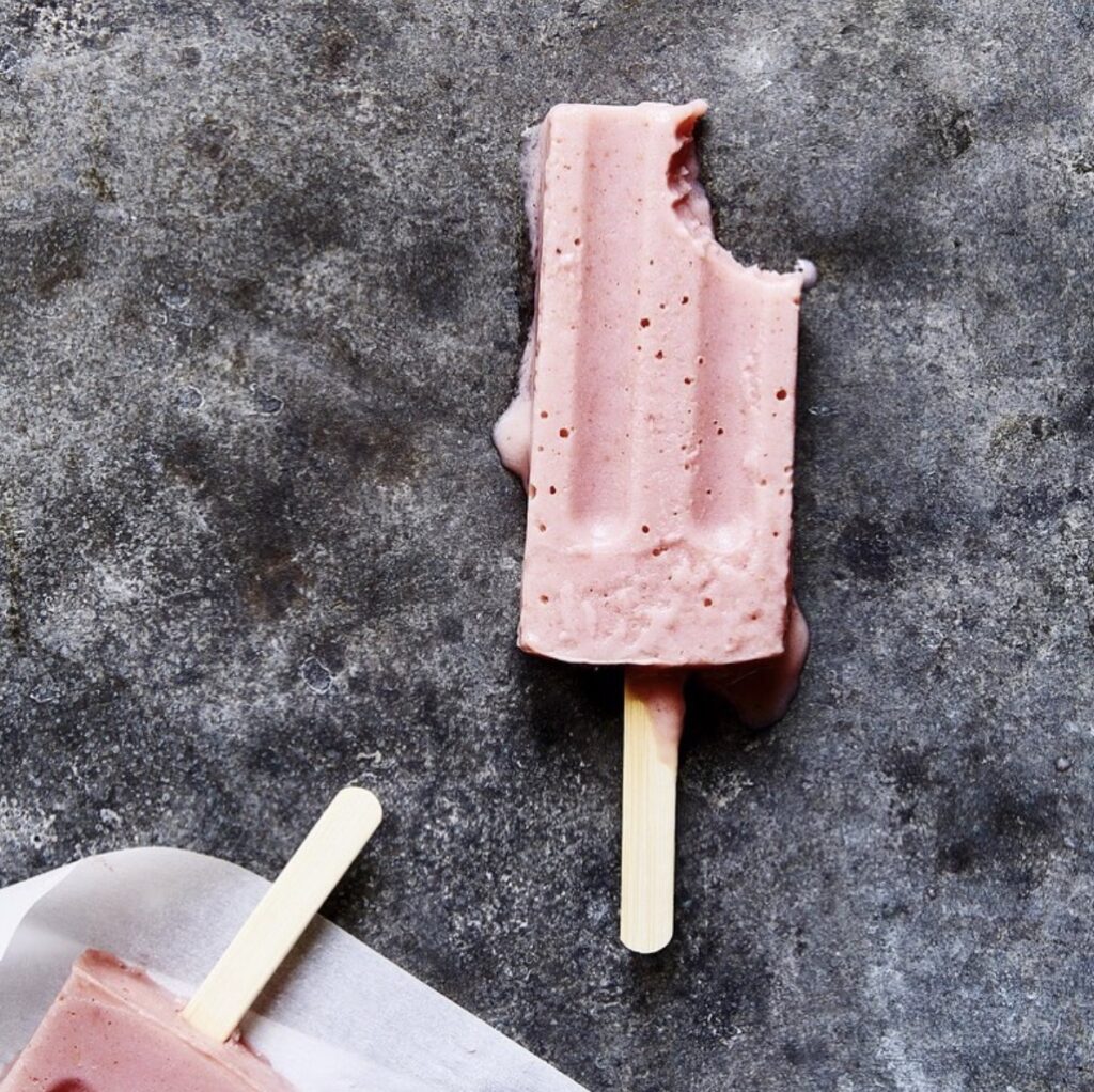 Strawberry Banana Yogurt Popsicle slightly melting on a gray table