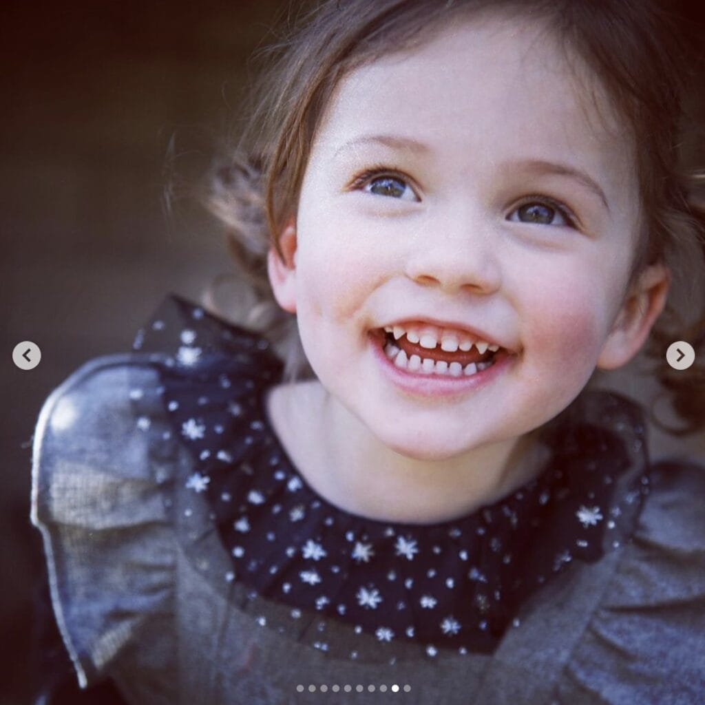 up close picture of young girl smiling gleefully while looking up, looking off camera