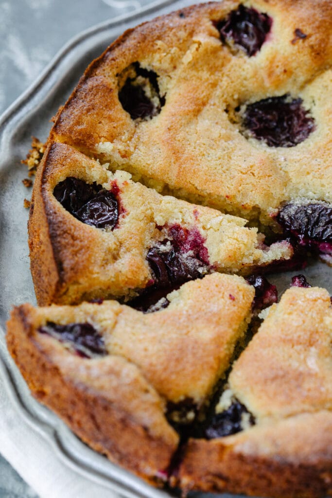 Cardamom Plum Buckle sliced on a platter on gray table