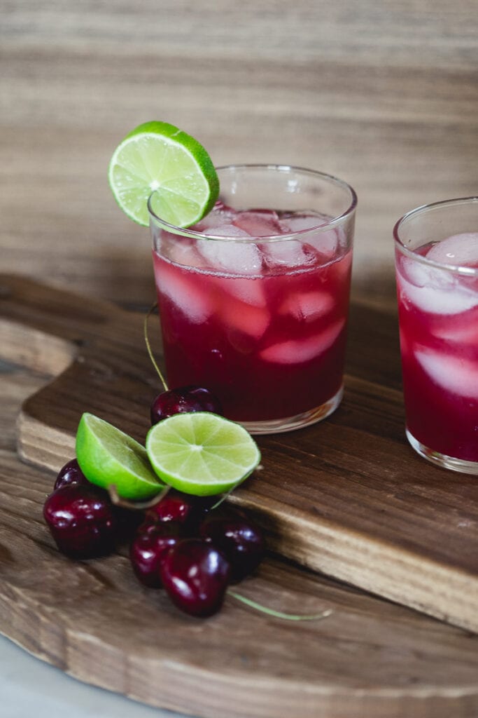 Glasses filled with ice and Sugar-Free Cherry Limeade, garnished with a slice of slime