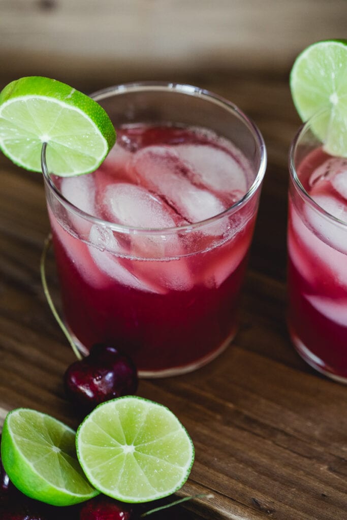 Glasses filled with ice and Sugar-Free Cherry Limeade, garnished with a slice of slime