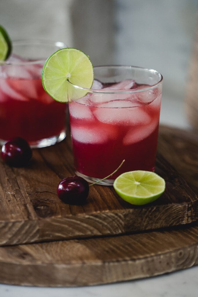 Glasses filled with ice and Sugar-Free Cherry Limeade, garnished with a slice of slime