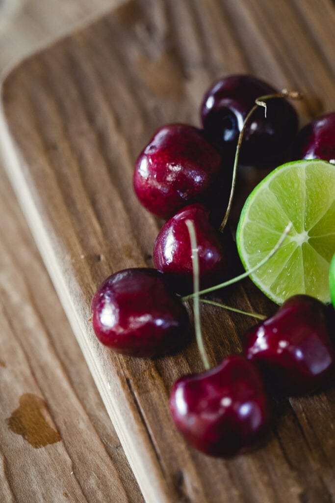 Cherries and lime on a wooden cutting board 