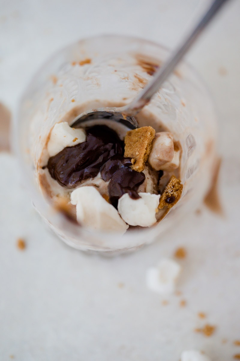 view of inside of a small glass that contains dairy-free s'mores ice cream with bits of marshmallow and pieces of graham crackers