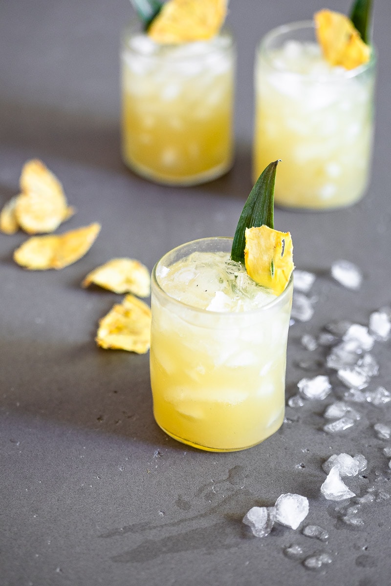 Vanilla Pineapple Margarita in a clear glasses full of ice, garnished with a pineapple slice and leaf