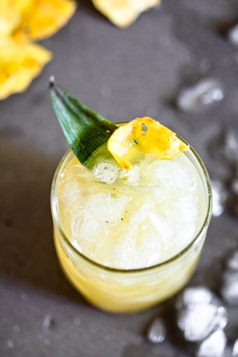 Vanilla Pineapple Margarita in a clear glass full of ice, garnished with a pineapple slice and leaf