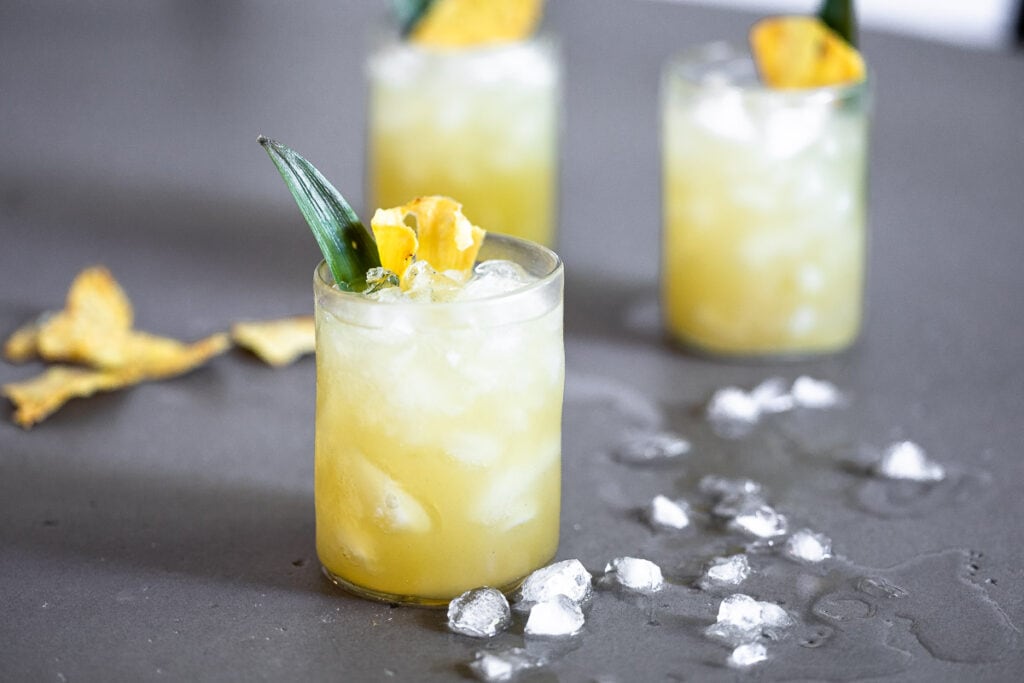 Vanilla Pineapple Margarita in clear glasses full of ice, garnished with a pineapple slice and leaf