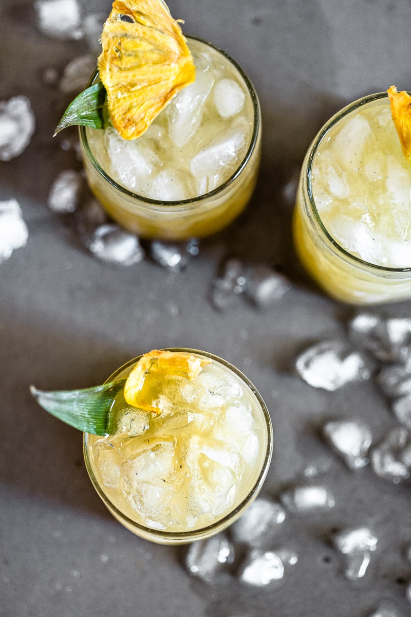 Vanilla Pineapple Margarita in clear glasses full of ice, garnished with a pineapple slice and leaf