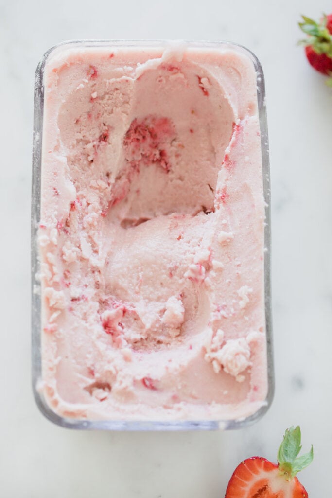 dairy free strawberry ice cream in glass rectangle container on white counter 