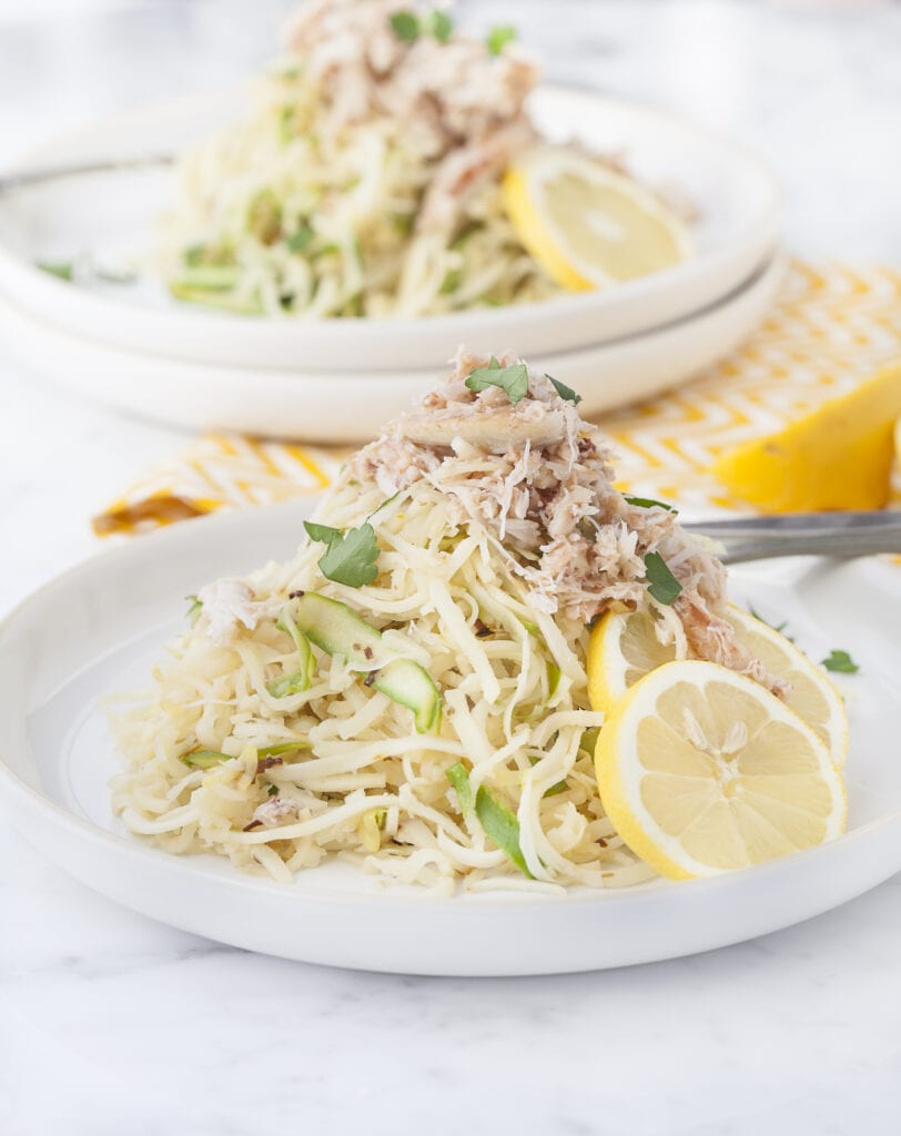Crab and Asparagus Linguine on a white plate served with slices of lemon