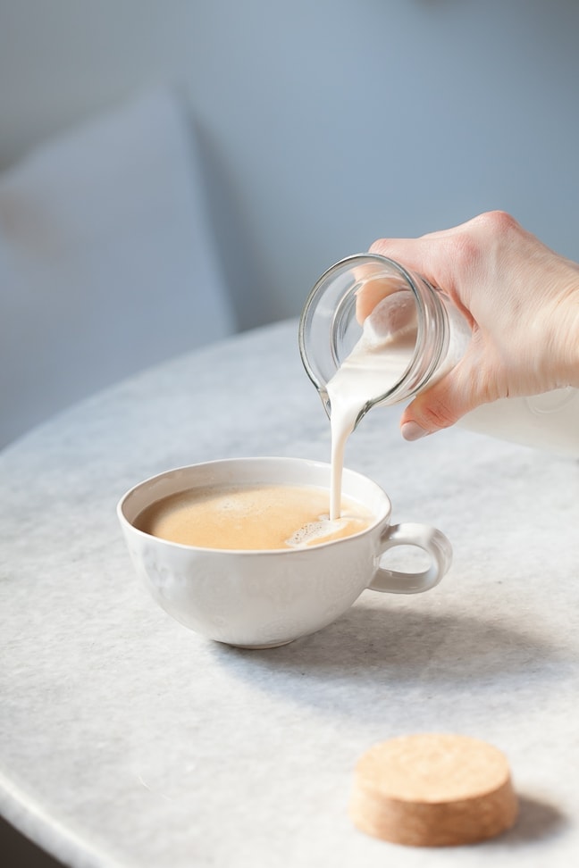 homemade dairy free creamer being poured into a cup of coffee