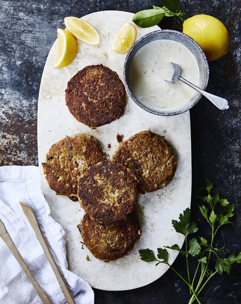 freshly made crab cakes with a remoulade sauce and lemon slices on the side 